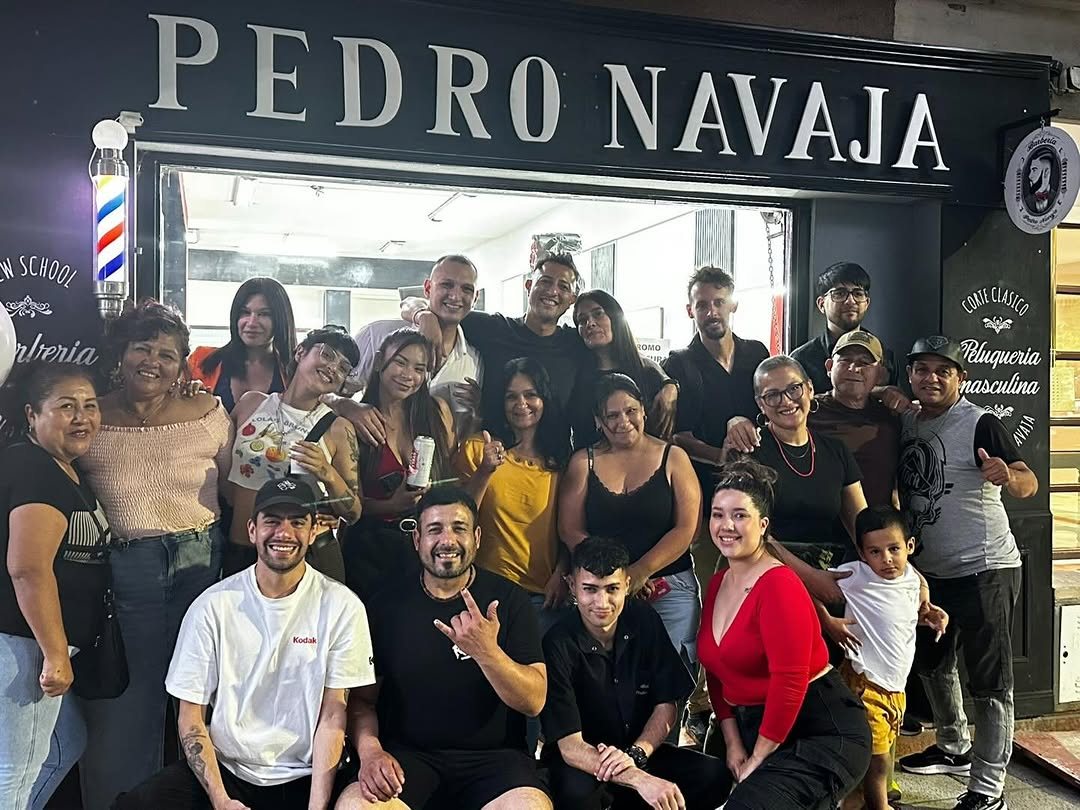 El equipo de barberos y clientes de Pedro Navaja frente al cartel de la sucursal Almagro